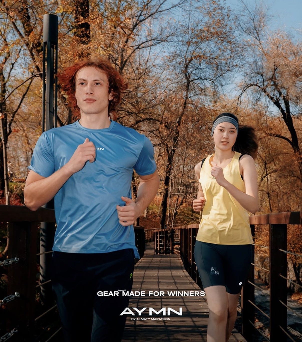 Two runners in Almaty Marathon Store sportswear on an autumn footbridge